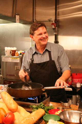 Photo of Chef Warren Caterson cooking and smiling.