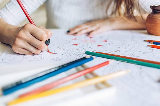 Woman with colored pencils doodling a zentangle pattern.